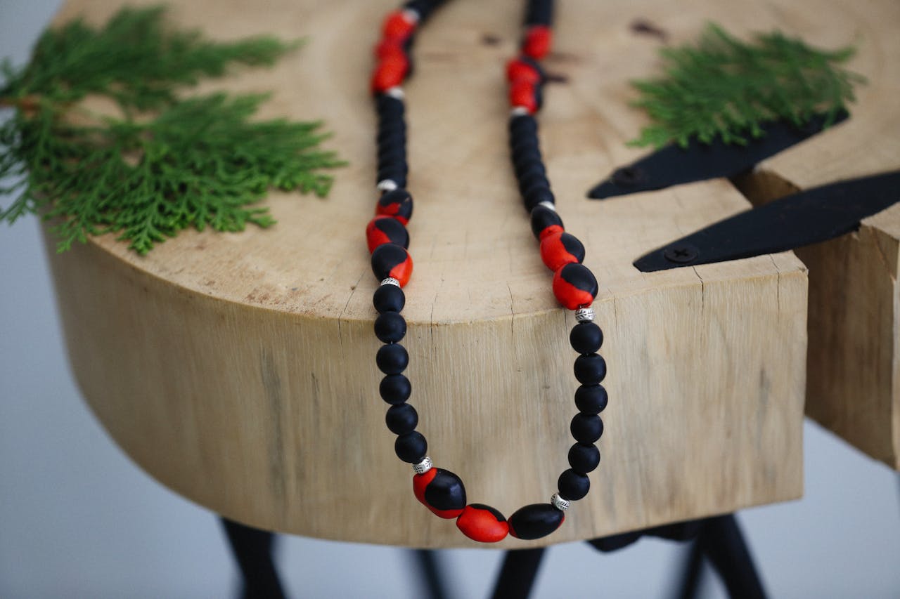 Stylish handmade bead necklace displayed elegantly on a natural wooden surface with greenery.